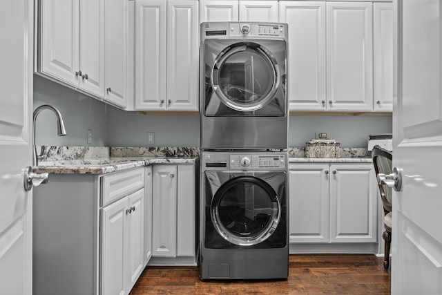 laundry room featuring cabinets, stacked washer and dryer, sink, and dark hardwood / wood-style floors