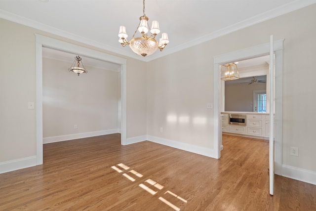 unfurnished dining area with hardwood / wood-style flooring, ornamental molding, and ceiling fan with notable chandelier