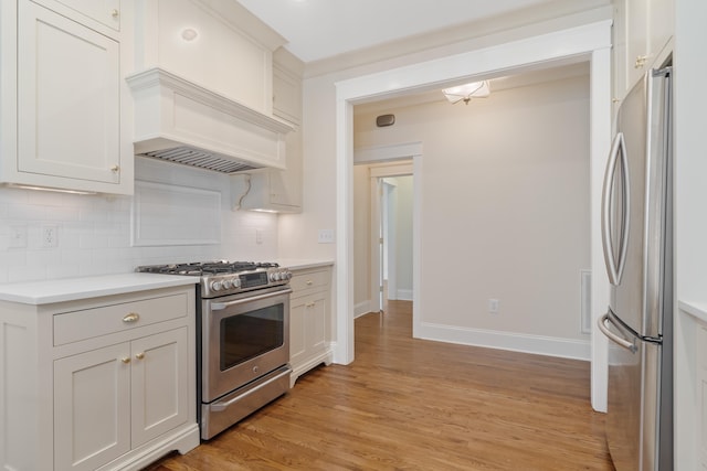 kitchen with white cabinetry, stainless steel appliances, tasteful backsplash, light hardwood / wood-style floors, and custom exhaust hood