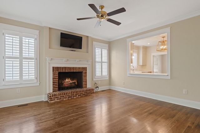 unfurnished living room featuring hardwood / wood-style flooring, a fireplace, ornamental molding, and ceiling fan