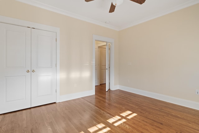 unfurnished bedroom with ornamental molding, hardwood / wood-style floors, ceiling fan, and a closet