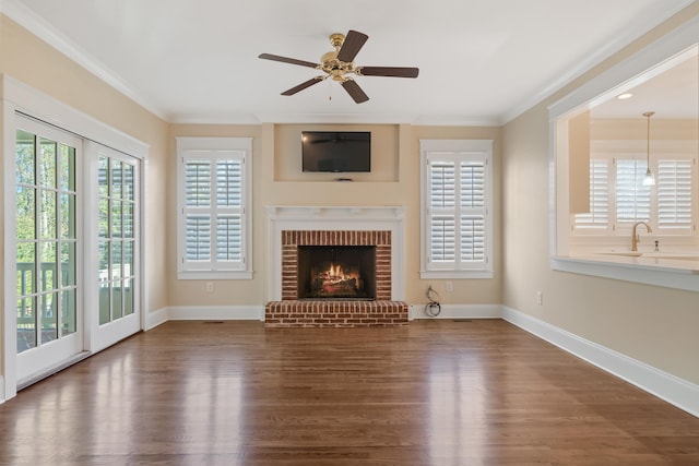 unfurnished living room with sink, dark wood-type flooring, ceiling fan, ornamental molding, and a brick fireplace