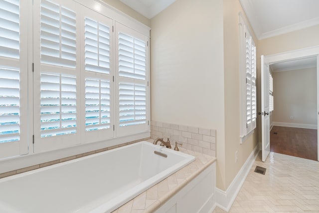 bathroom featuring tiled tub, crown molding, and plenty of natural light