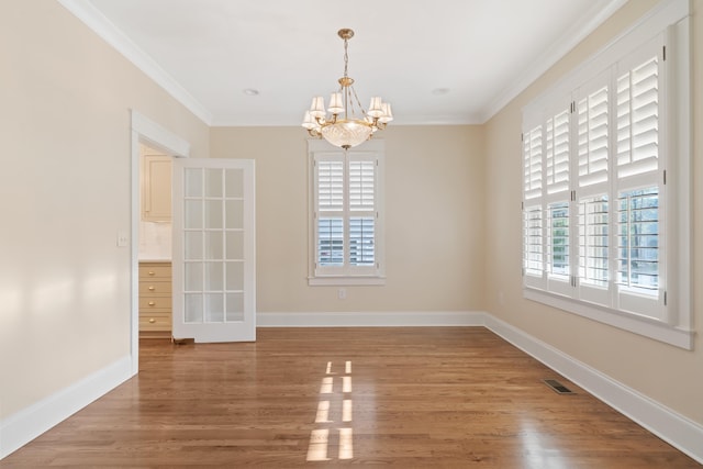 unfurnished dining area with crown molding, wood-type flooring, and an inviting chandelier