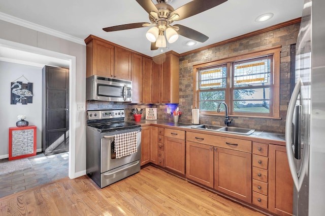 kitchen featuring appliances with stainless steel finishes, tasteful backsplash, sink, ornamental molding, and light wood-type flooring