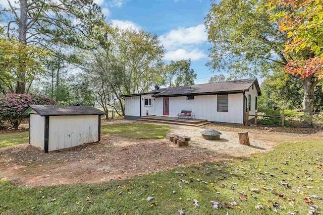 back of house featuring a wooden deck, a storage unit, a yard, and an outdoor fire pit