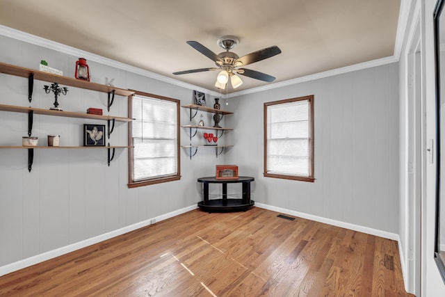 empty room featuring crown molding, ceiling fan, a healthy amount of sunlight, and light wood-type flooring