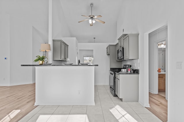 kitchen featuring stainless steel microwave, black range with electric cooktop, dark countertops, and gray cabinetry