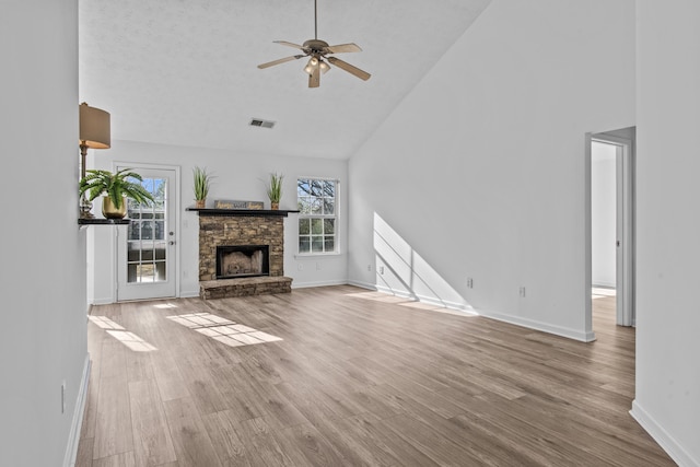 unfurnished living room featuring baseboards, a fireplace, high vaulted ceiling, and wood finished floors