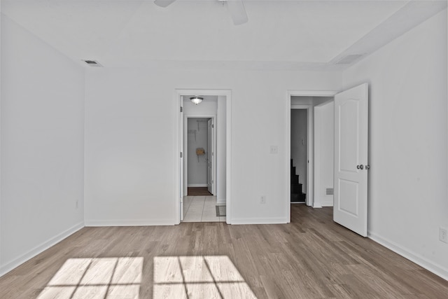 unfurnished bedroom with ceiling fan, wood finished floors, visible vents, and baseboards