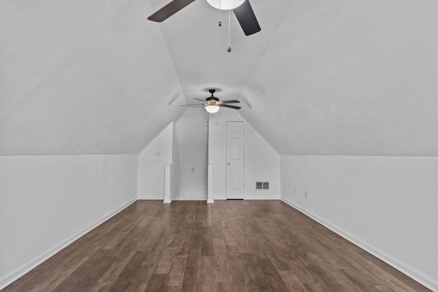 bonus room featuring lofted ceiling, dark wood-style flooring, a ceiling fan, visible vents, and baseboards