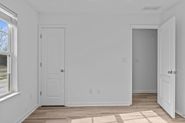 spare room featuring baseboards, visible vents, and light wood-style floors