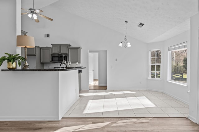 kitchen featuring visible vents, dark countertops, stainless steel microwave, gray cabinets, and a textured ceiling