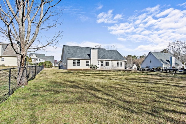 back of property with a fenced backyard, a yard, and a chimney