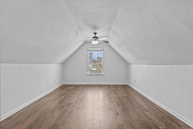 additional living space featuring vaulted ceiling, a textured ceiling, baseboards, and wood finished floors