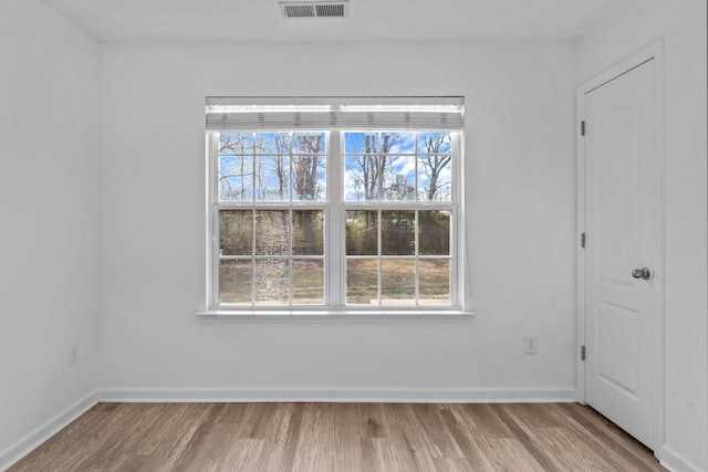 spare room featuring baseboards, visible vents, and wood finished floors