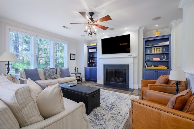 living room featuring ornamental molding, ceiling fan, light wood-type flooring, and built in shelves