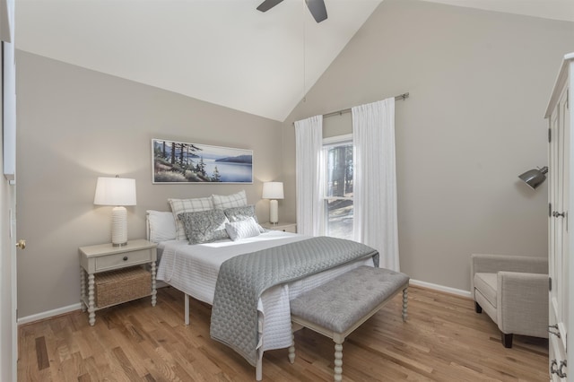 bedroom with ceiling fan, light wood-style floors, baseboards, and high vaulted ceiling