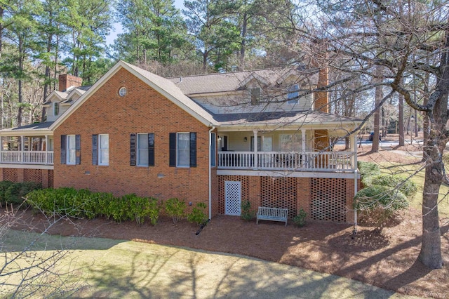 view of front of home with a porch, brick siding, and a chimney