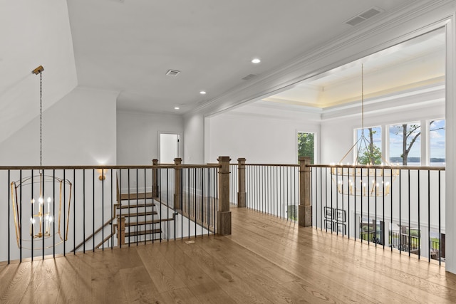 corridor with visible vents, an inviting chandelier, crown molding, and wood finished floors