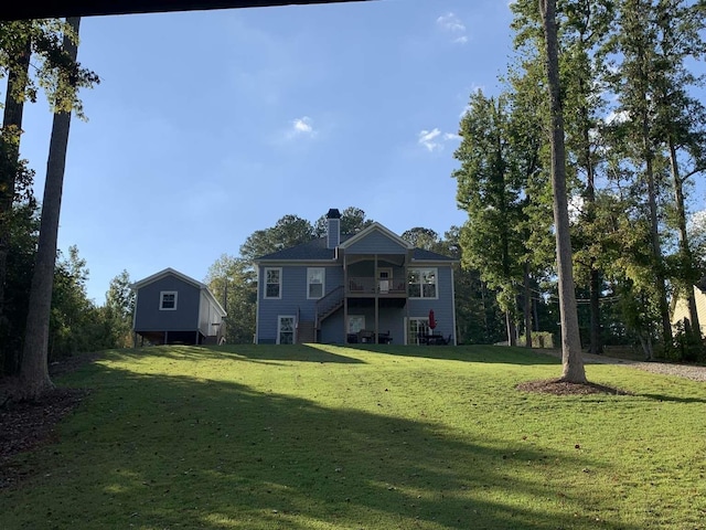 back of house with stairway, a yard, and a chimney