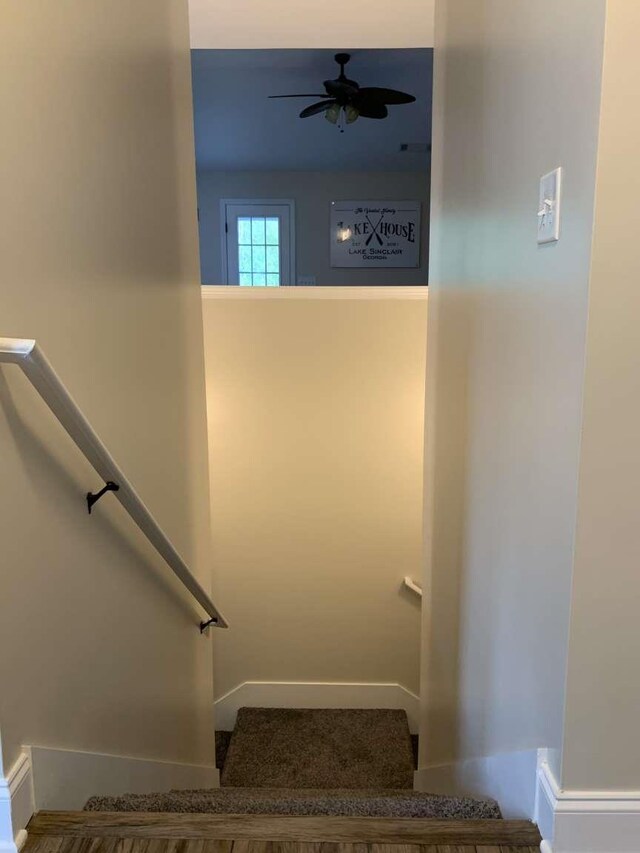 stairway featuring a ceiling fan and baseboards