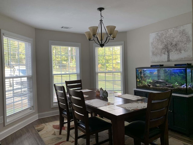 dining area featuring a notable chandelier, plenty of natural light, visible vents, and wood finished floors