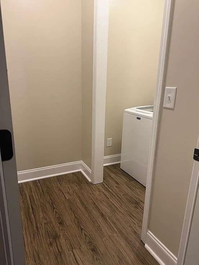 laundry room with dark wood-style floors, laundry area, washer / dryer, and baseboards