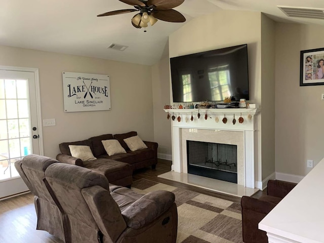 living area with visible vents, lofted ceiling, a fireplace, wood finished floors, and a ceiling fan