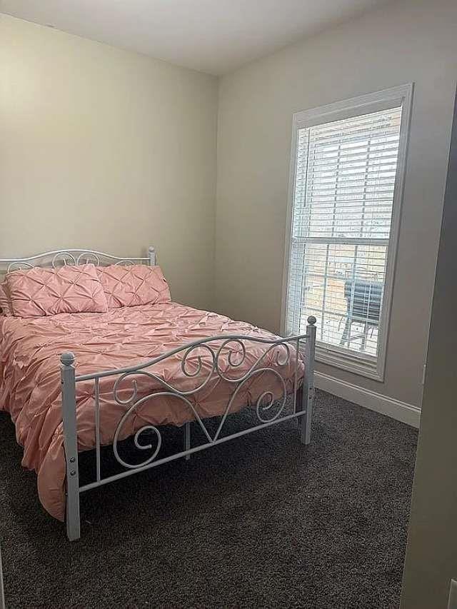 carpeted bedroom with multiple windows and baseboards