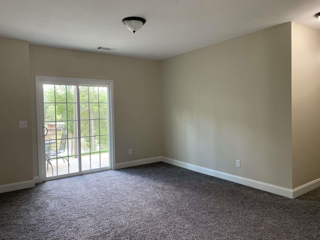 spare room featuring visible vents, baseboards, and dark carpet