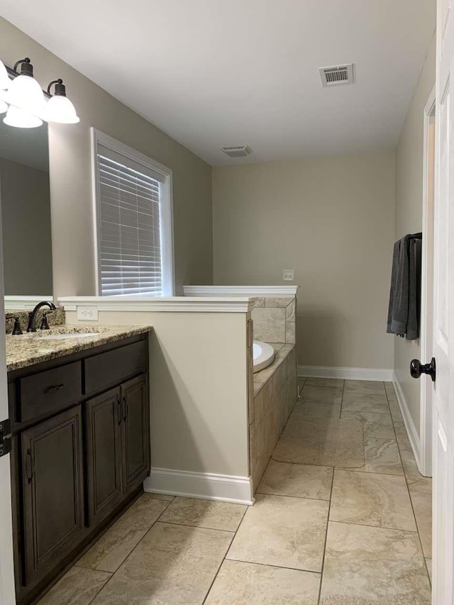 bathroom with vanity, a bath, baseboards, and visible vents