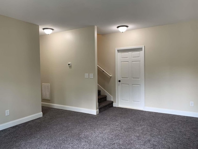 spare room featuring visible vents, stairway, baseboards, and dark colored carpet