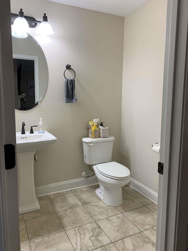 half bath featuring tile patterned floors, toilet, and baseboards