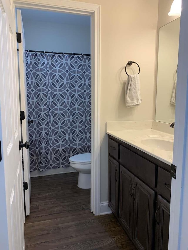 full bathroom with a shower with curtain, toilet, wood finished floors, and vanity