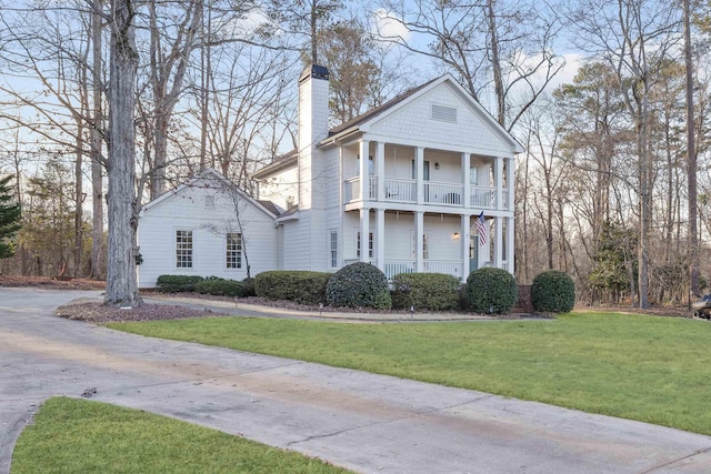 neoclassical home with a balcony and a front lawn