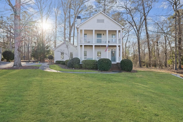 view of front facade featuring a porch, a balcony, and a front yard