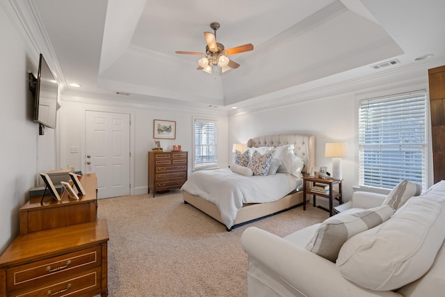 carpeted bedroom with crown molding, a tray ceiling, and ceiling fan