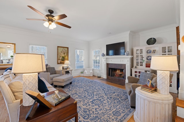 living room with hardwood / wood-style floors, ornamental molding, a tile fireplace, and ceiling fan