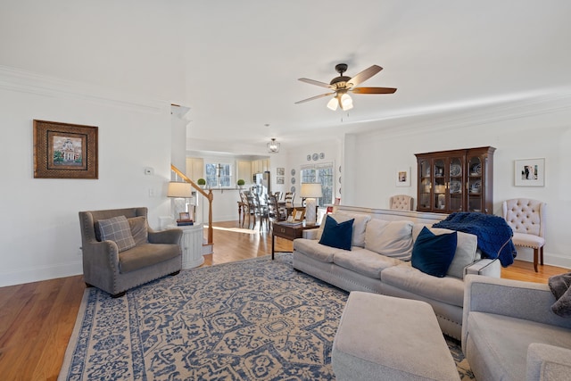 living room featuring wood-type flooring, ornamental molding, and ceiling fan