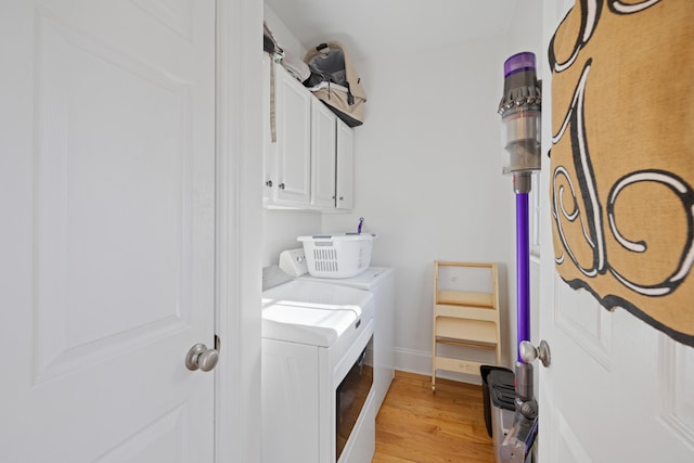 clothes washing area with cabinets, washing machine and dryer, and light wood-type flooring