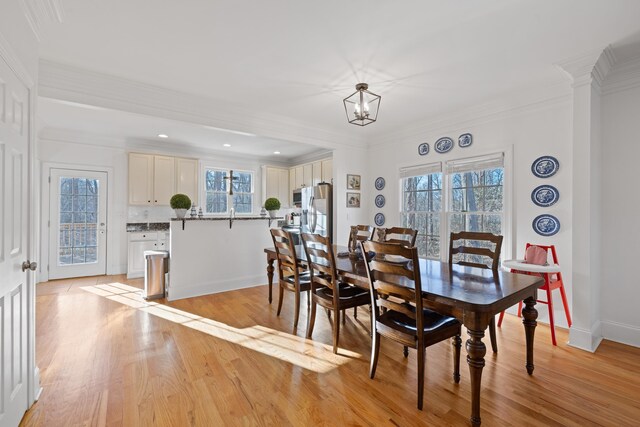 dining room featuring ornamental molding, a notable chandelier, a wealth of natural light, and light hardwood / wood-style floors