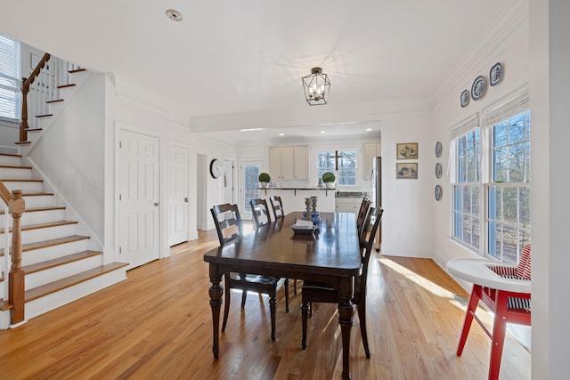 dining space with crown molding, plenty of natural light, a chandelier, and light hardwood / wood-style floors