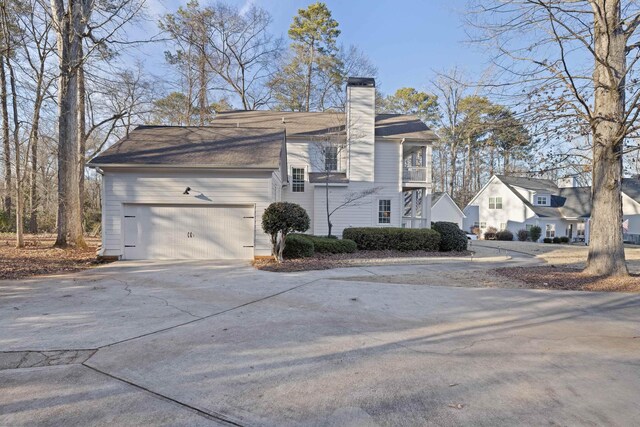 view of side of property featuring a balcony and a garage