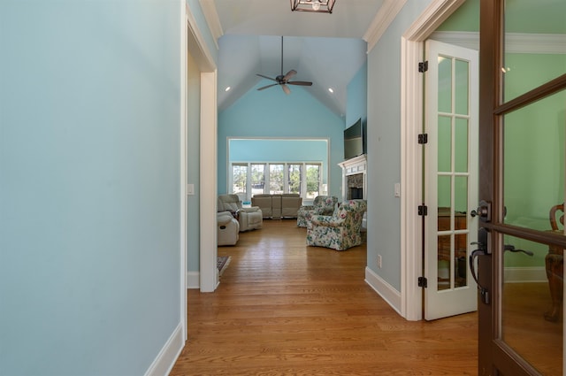 corridor featuring high vaulted ceiling, ornamental molding, light hardwood / wood-style floors, and french doors