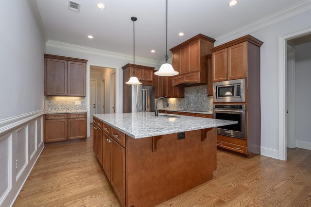1020 Fairway Ridge Cir, Greensboro, GA 30642 - kitchen with stainless steel appliances, a sink, light wood-style floors, light stone counters, and an island with sink