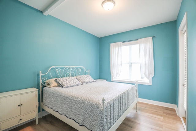 bedroom with hardwood / wood-style flooring and beamed ceiling