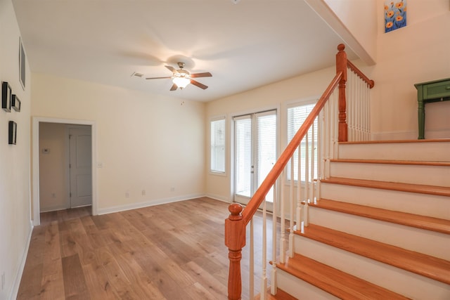 stairs featuring wood-type flooring and ceiling fan