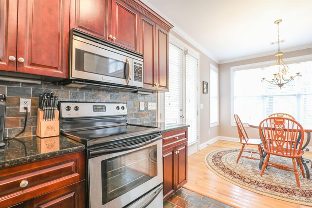 kitchen with appliances with stainless steel finishes, dark stone countertops, backsplash, dark hardwood / wood-style floors, and ornamental molding