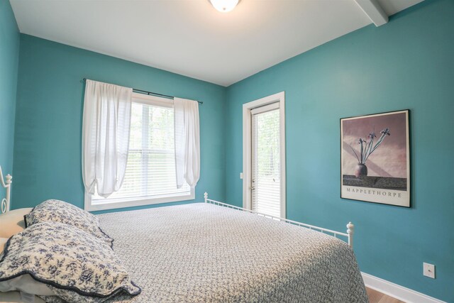 bedroom with hardwood / wood-style floors and beam ceiling